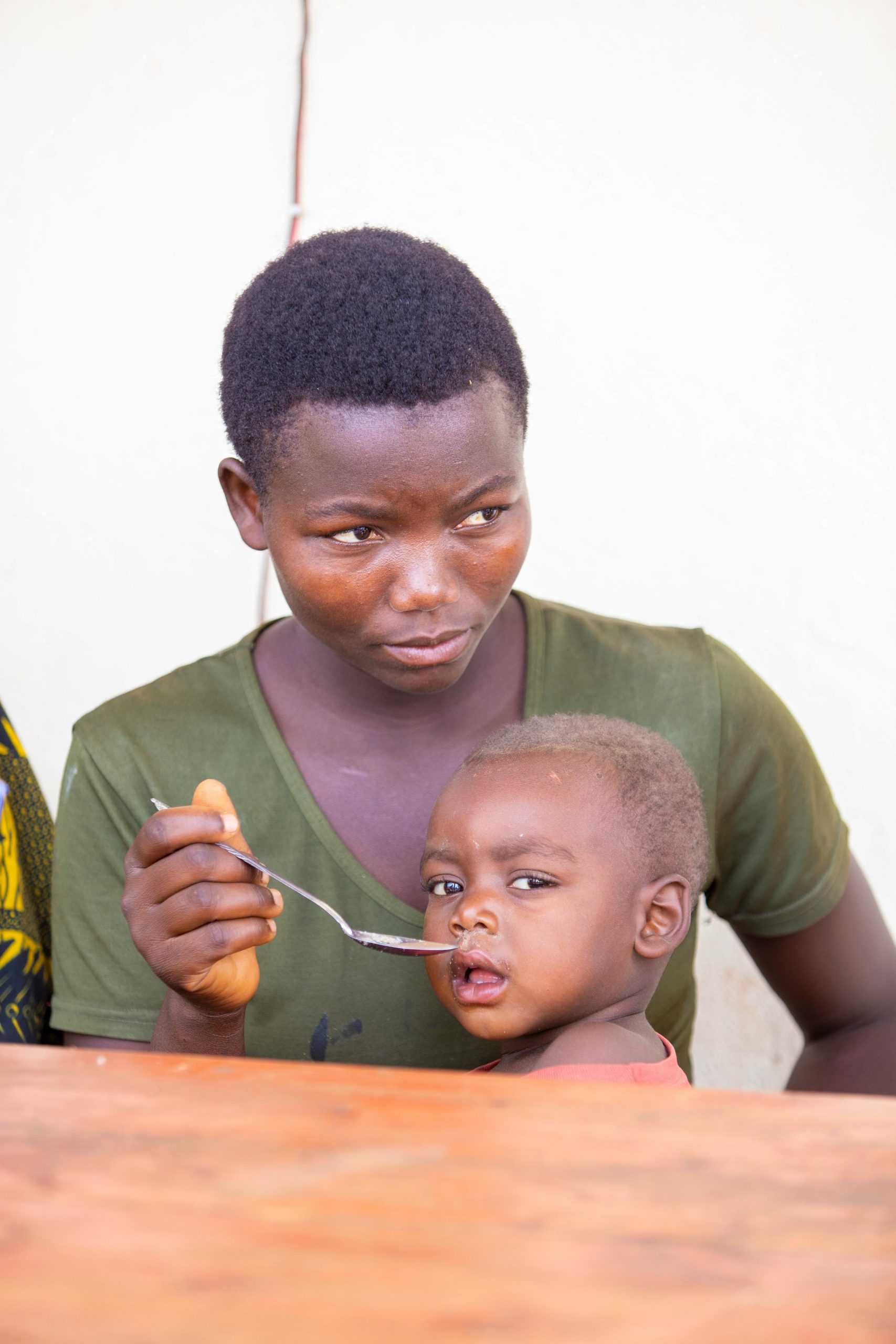 A caring mother feeding her young child indoors, depicting love and care.