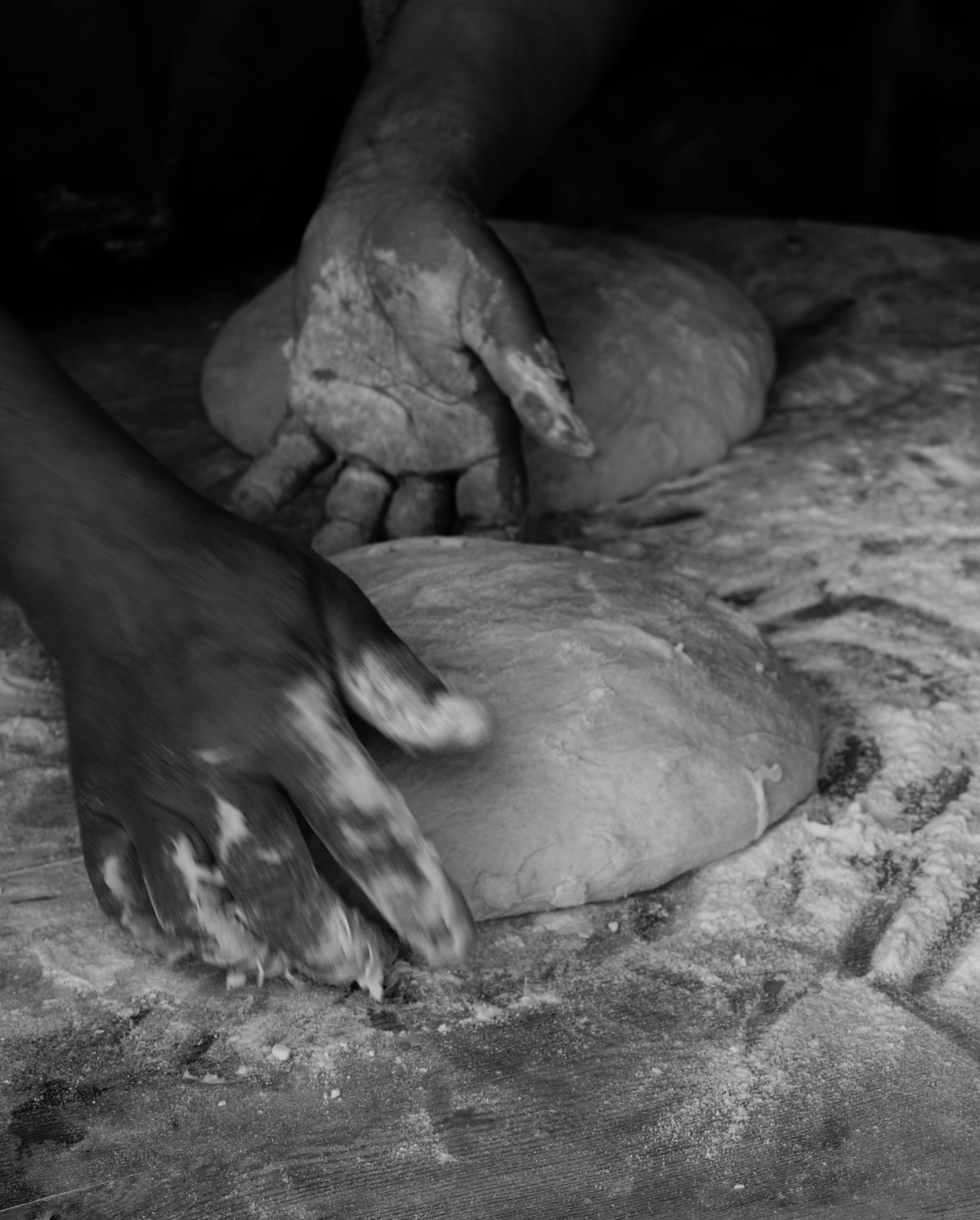 Monochrome image of a baker's hands expertly kneading dough, highlighting traditional bread-making.